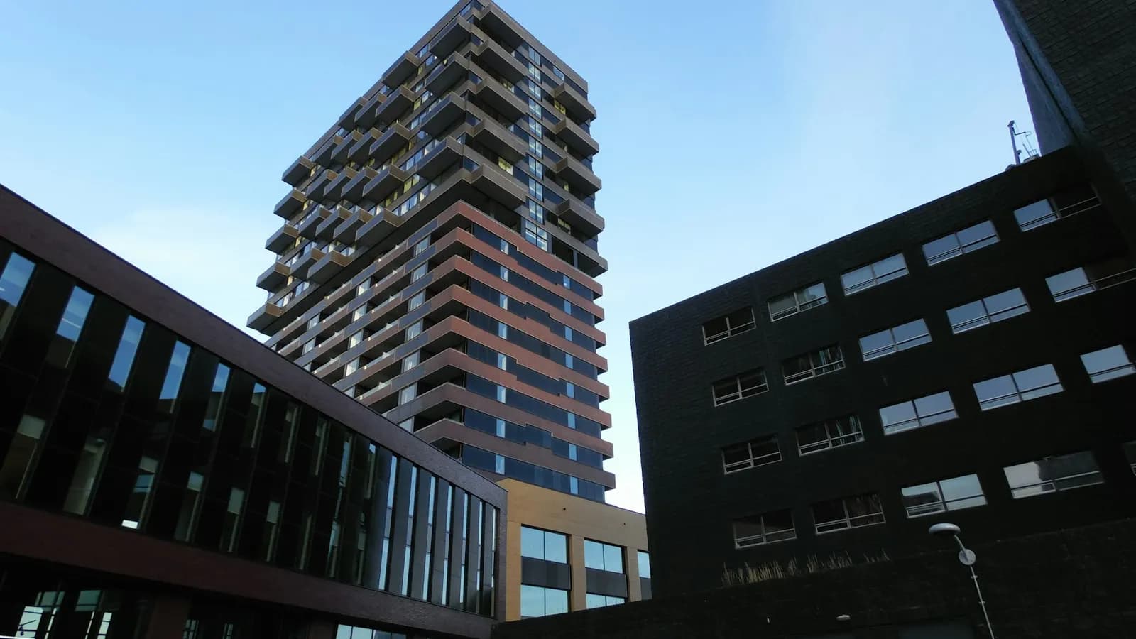 Woontoren met balkons tussen gebouwen onder een heldere lucht